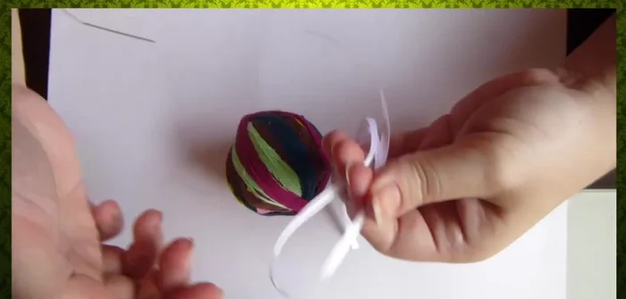 Cortar las cintas en mitades y coserlas a la pelota para crear flecos.