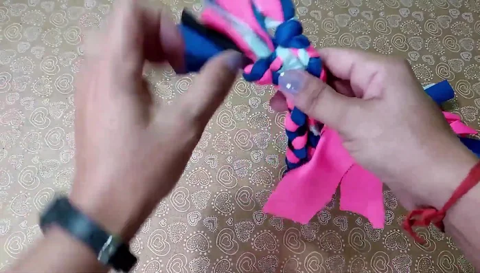 Unir las tres trenzas: Con un trozo corto de tela, une las tres trenzas hechas previamente con un nudo firme.