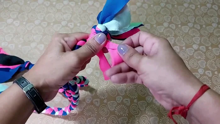 Nudo final y detalles: Al final de la trenza grande, asegúrala con otro nudo. Corta los extremos en pequeñas tiras para crear flecos.