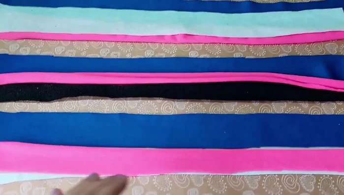 Cortar tiras de tela: Corta tiras de tela de aproximadamente 3-2 centímetros de ancho y 60 centímetros de largo. Necesitarás 9 tiras en total, de diferentes colores para hacerlo más divertido.