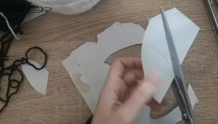 Crear la nariz: Recortar un triángulo de cartón, forrarlo con lana rosa, y pegarlo en la cara.