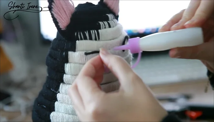 Añadir detalles: Pegar los ojos (lana), la nariz y la boca; y colocar los bigotes (cerdas de brocha).