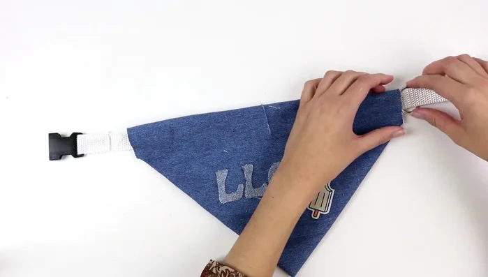 Pasar el collar por el hueco de la banderilla y la anilla por el corte de la tela.