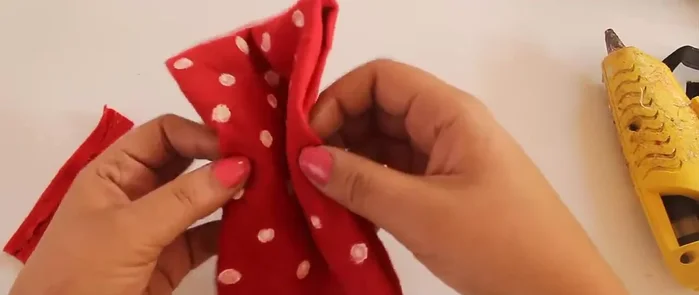 Dobla la pieza pequeña hacia adelante por la mitad, dobla las orillas hacia atrás y pega la tira pequeña por detrás con silicón caliente.