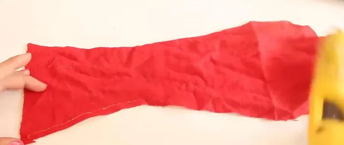 Dobla las orillas y pégalas con silicón caliente. Haz lo mismo con una tira pequeña para el cierre.