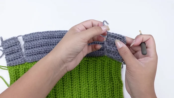 Tejer medios puntos altos para unir las piezas, creando las mangas.