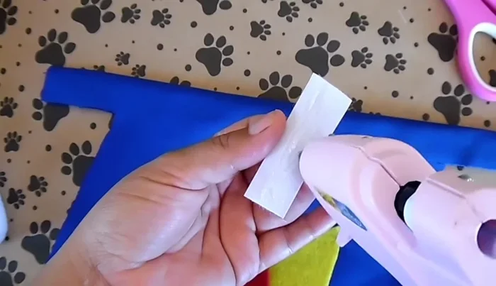 Cortar dos trozos de velcro de 2 pulgadas y colocarlos en los lados de la capa para sujetarla.