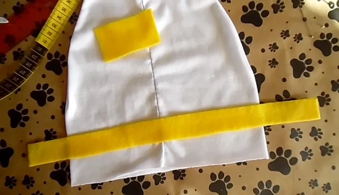 Cortar dos círculos para las patas del gato. Pegar velcro en la parte trasera de la playera y en la capa para unirlas.