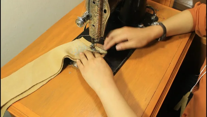 Cosiendo los hinchitos laterales: Cose las tiras para los hinchitos laterales, dobla y cose una línea inclinada para formarlos. Coloca los hinchitos debajo del cuello y a la mitad de la capa.