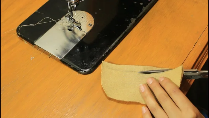 Dale forma a la boina: Marca la mitad y 1 cm hacia abajo, haz una curva para darle figura. Coloca un botón en el centro.