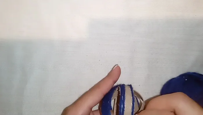 Terminar el recubrimiento: Continuar aplicando silicón e hilo hasta cubrir toda la pelota, cortando y pegando la punta del hilo al final.