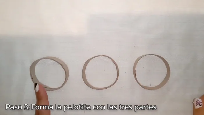 Formar la base de la pelota: Colocar tres piezas de cartón formando una pelota, asegurándose de que encajen.