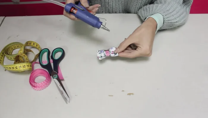 Añadir la pinza o elástico: Pegar una pinza para el pelo o un elástico con silicona caliente a la parte trasera del moño.