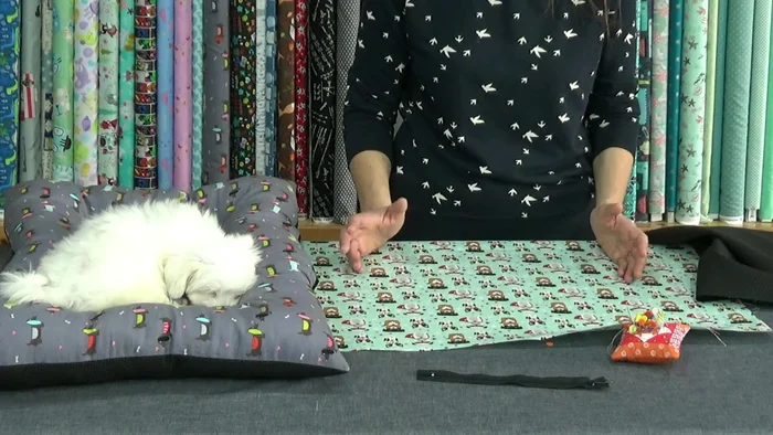 Colocar la cremallera: Centra la tela y la suela antideslizante. Coloca el derecho de la cremallera con el derecho de la tela, haciendo coincidir los centros. Sujeta con alfileres.