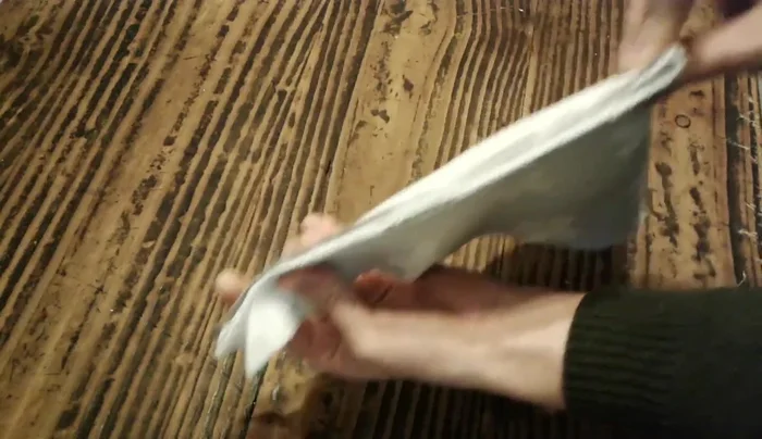 Plegar y marcar: Plegar la tela llevando una punta sobre la otra por el borde más largo. Marcar una línea curva con una lapicera para la forma del cuello.