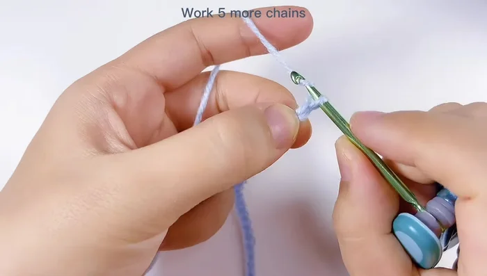 Realizar punto alto doble en la primera cadena de las últimas 5, saltar dos cadenas y tejer un punto alto doble en el tercer espacio. Repetir este patrón (2 cadenas, punto alto doble) hasta el final de la fila.