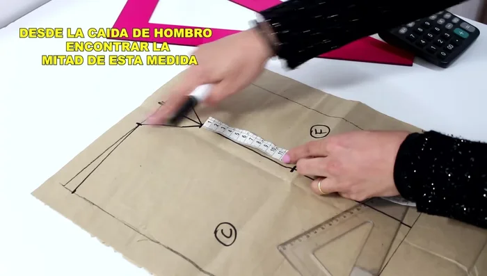 Encuentra el punto medio entre la caída del hombro y el punto marcado previamente. A partir de este punto, sal 2 cm hacia el frente y 1.5 cm hacia atrás. Dibuja una curva suave que conecte estos puntos.