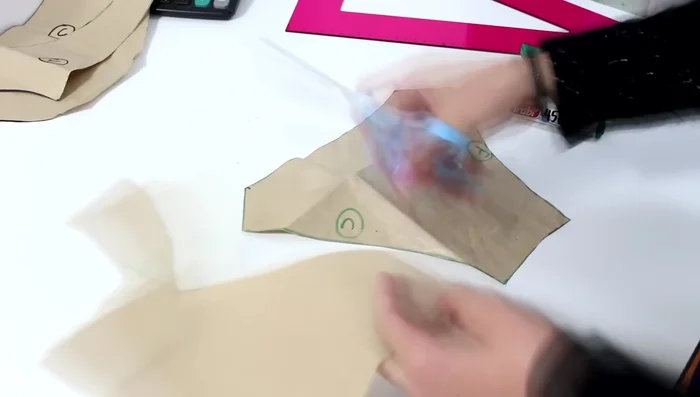 Desde la esquina superior derecha, baja 2 cm. Desde el mismo punto superior, baja 7 cm. Luego, sube 1.5 cm desde ese punto y traza una línea curva para formar la capucha.