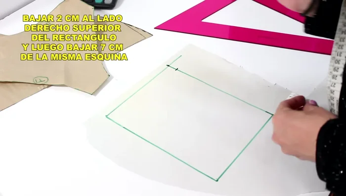 Desde la esquina superior derecha, baja 2 cm. Desde el mismo punto superior, baja 7 cm. Luego, sube 1.5 cm desde ese punto y traza una línea curva para formar la capucha.