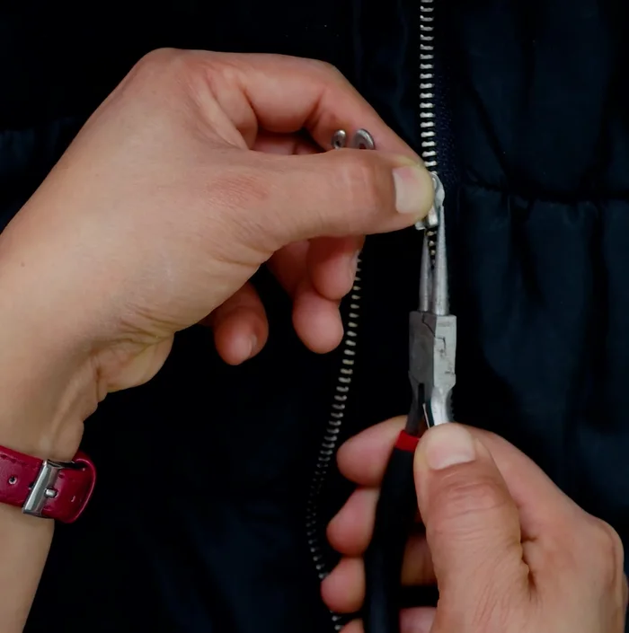 Si la cremallera está ligeramente abierta, utiliza una pinza de bisutería para presionar suavemente cada lado del cierre, cerrando la brecha.