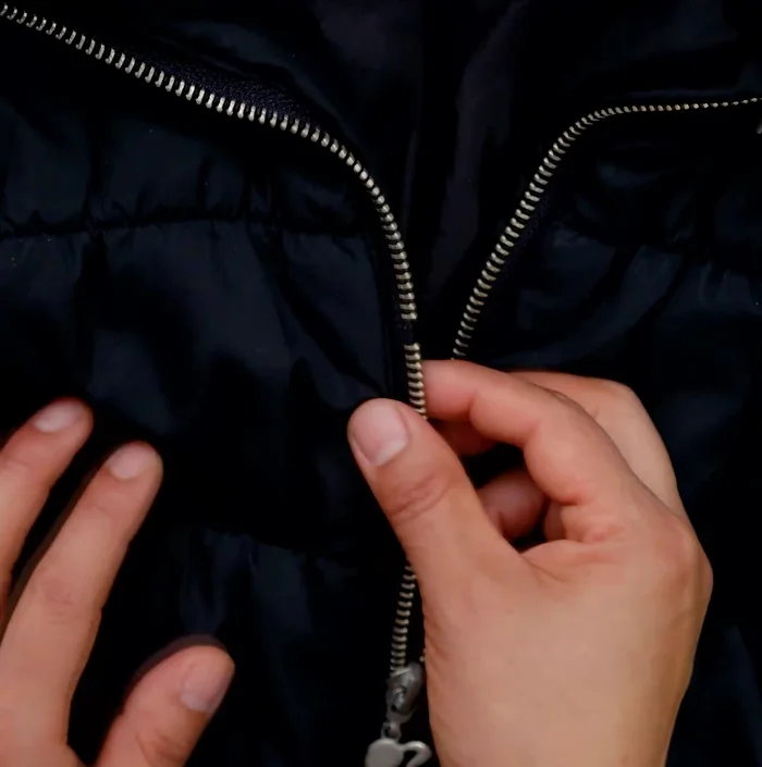 Retira el tope superior de la cremallera de ambos lados.